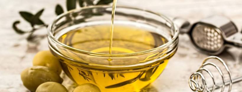 de l'huile d'olive dans un bol en verre près de quelques olives